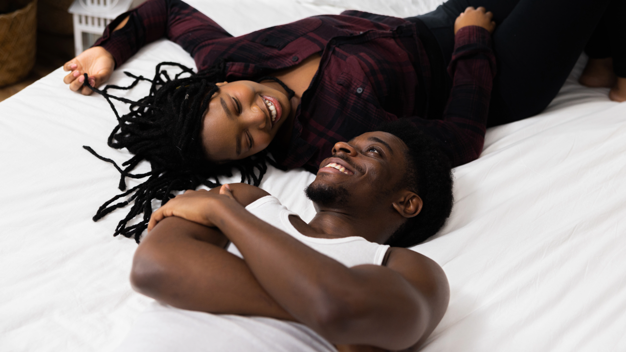 Happy man and woman laying in bed smiling at each other